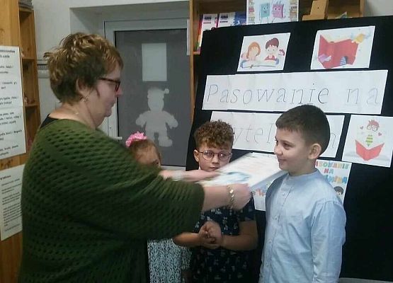 Grafika 3: "W KRÓLESTWIE KSIĄŻEK" - Pasowanie na czytelnika uczniów klasy pierwszej  w bibliotece szkolnej. NPRc 2.0